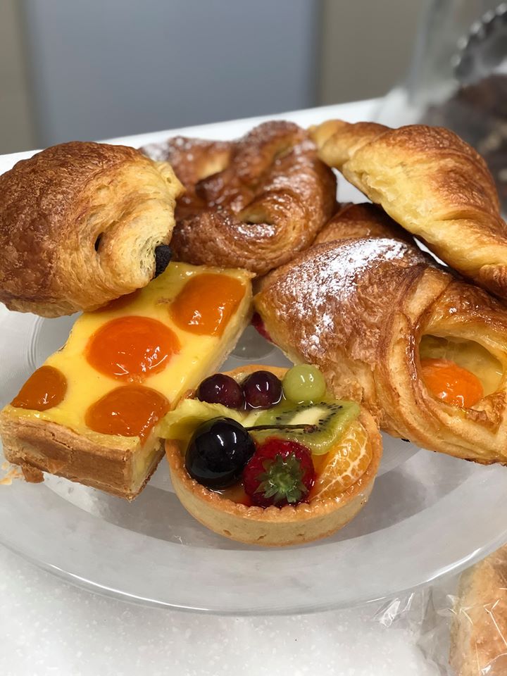 A photo of a plate of croissants, pain au chocolat, apricot pastries and fruit tarts