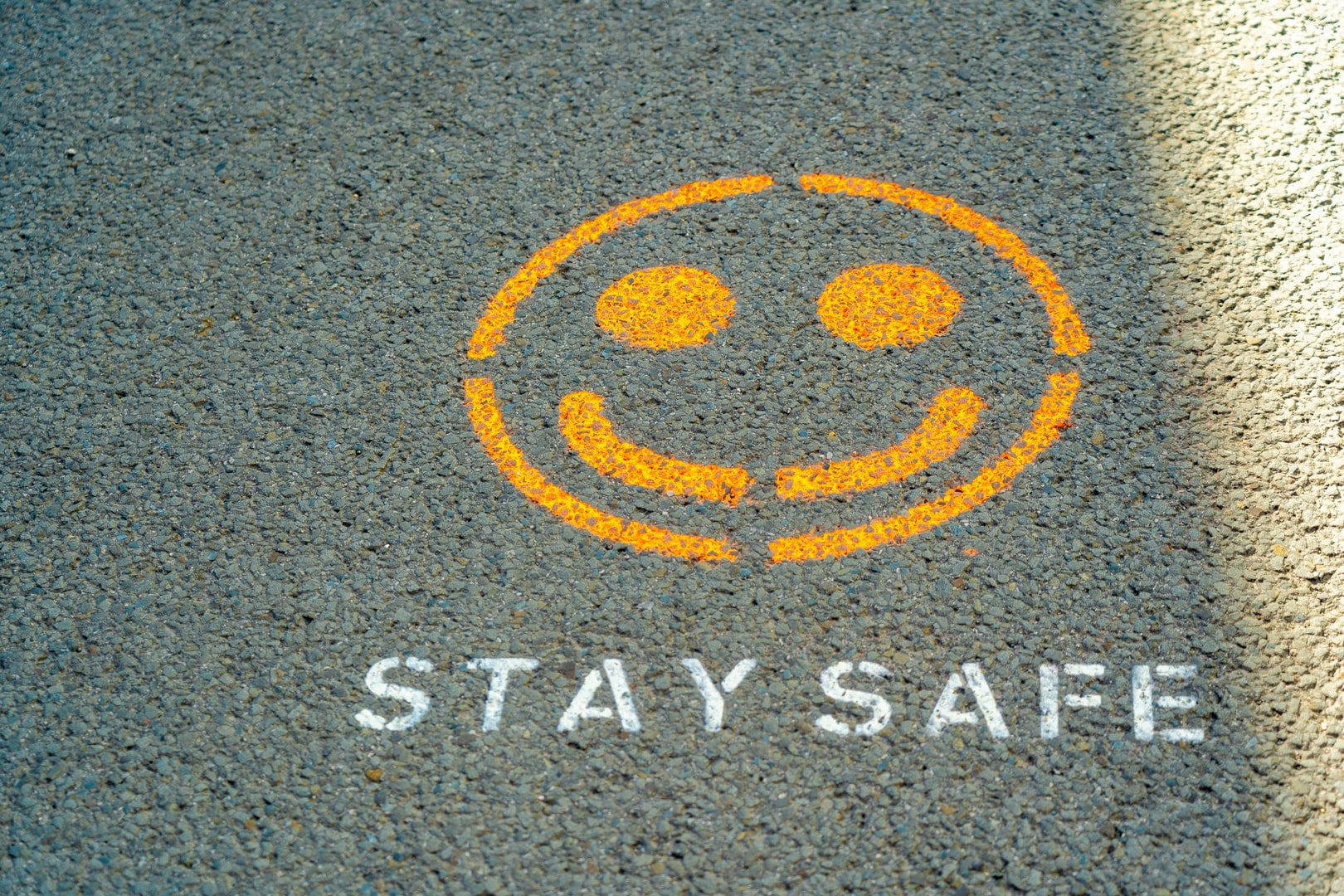 A smiley face emoji painted on a pavement with the words stay safe