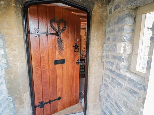 A photo of a wooden front door of a holiday cottage in Bretforton, slightly ajar with a heart decoration on the door