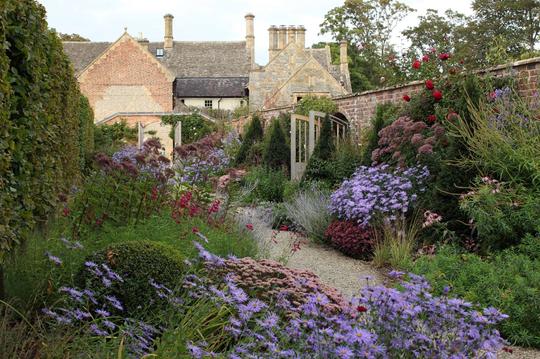 A photo of a path and beautiful flower beds in the grounds of Bretforton Manor with the historic manor building in the background