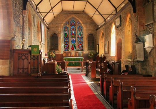 A photo of the historic interior of St Leonard's Bretforton, shot across the pews towards the altar