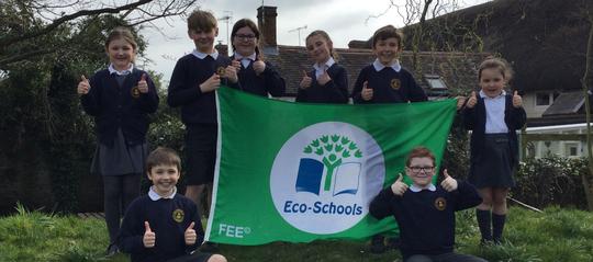Bretforton Village School pupils holding up a large green eco schools flag