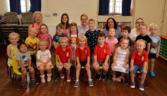 Children posing on chairs with the keyworkers at Bretforton pre school playgroup