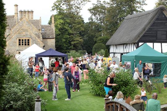 A photo of the crowds at Bretforton Show with Bretforton Manor, the Cider Barn and show stalls in the background