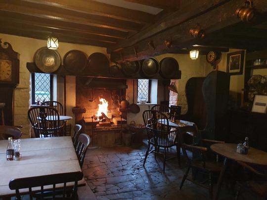 A photo of the historic interior of  The Fleece Inn Bretforton with tables and a roaring open fire